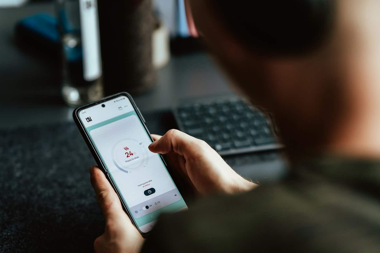 Persona usa un'app per smartphone per controllare il riscaldamento domestico.